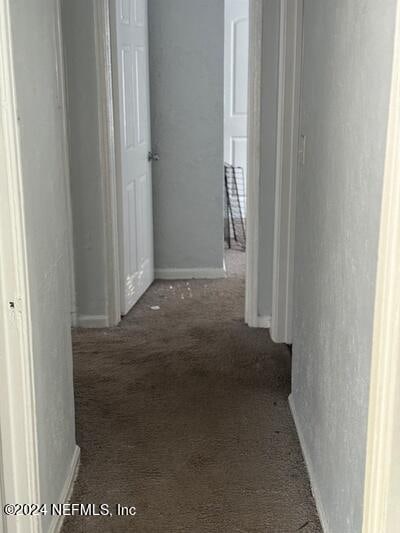 hall with dark colored carpet