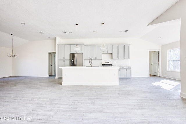 kitchen featuring an island with sink, stainless steel fridge, sink, decorative light fixtures, and vaulted ceiling