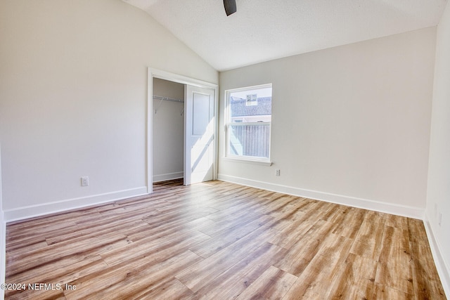 unfurnished bedroom featuring ceiling fan, light hardwood / wood-style flooring, a closet, vaulted ceiling, and a textured ceiling