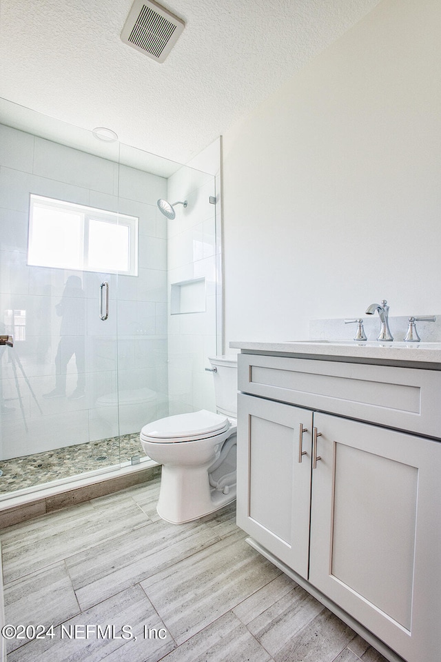 bathroom featuring hardwood / wood-style floors, toilet, vanity, and a shower with shower door