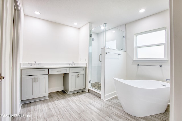 bathroom with hardwood / wood-style floors, vanity, independent shower and bath, and a textured ceiling