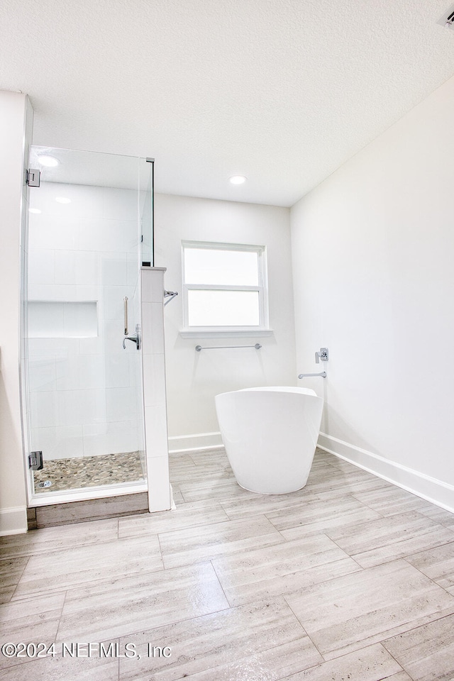 bathroom with hardwood / wood-style flooring, independent shower and bath, and a textured ceiling