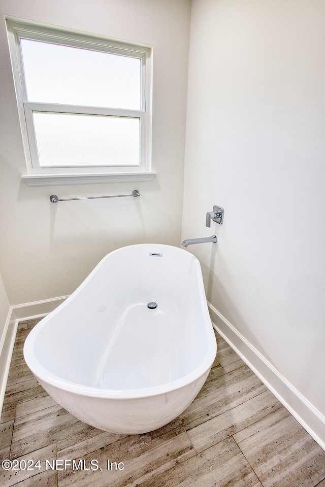 bathroom with wood-type flooring and a tub to relax in