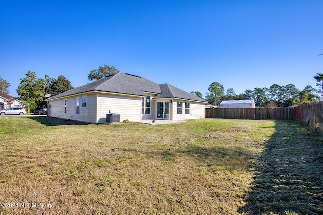 back of house with cooling unit and a lawn