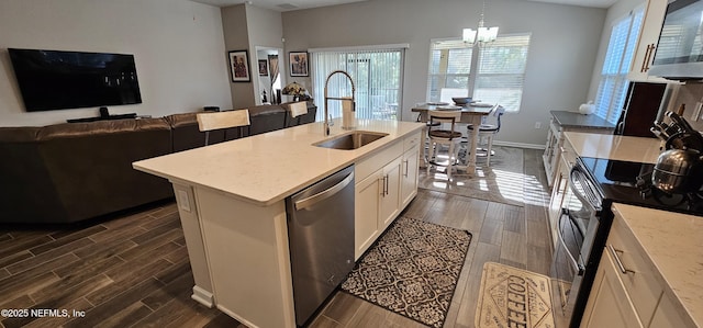 kitchen with decorative light fixtures, an island with sink, sink, a notable chandelier, and stainless steel appliances