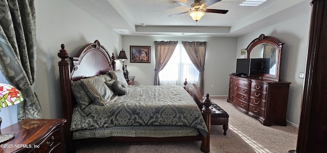 carpeted bedroom with ceiling fan, a raised ceiling, and a textured ceiling