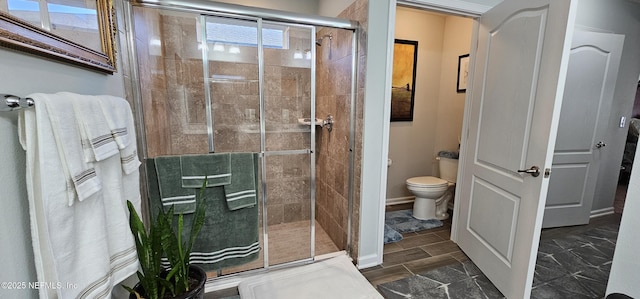 bathroom featuring a shower with shower door and toilet