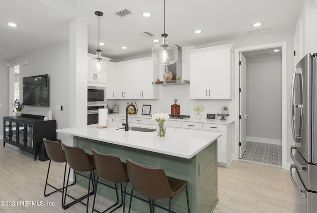 kitchen with appliances with stainless steel finishes, wall chimney exhaust hood, white cabinetry, and sink