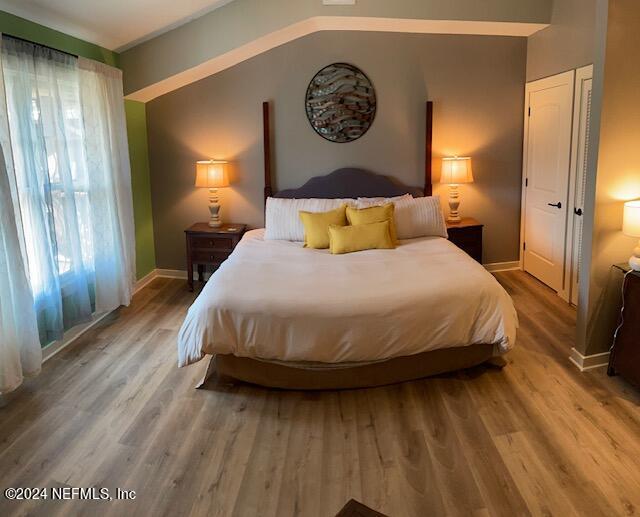 bedroom featuring vaulted ceiling, multiple windows, and hardwood / wood-style flooring