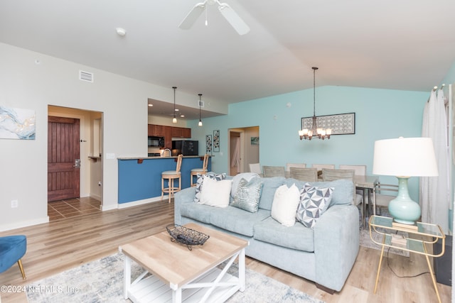 living room with lofted ceiling, ceiling fan with notable chandelier, and light hardwood / wood-style floors