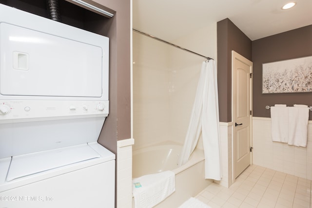 laundry area featuring light tile patterned floors and stacked washing maching and dryer