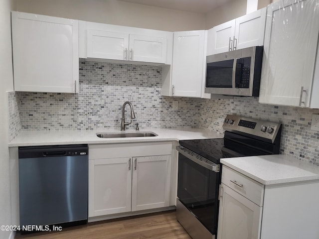 kitchen featuring appliances with stainless steel finishes, white cabinetry, sink, and light wood-type flooring