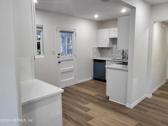 kitchen with black dishwasher, sink, light wood-type flooring, white cabinetry, and decorative backsplash