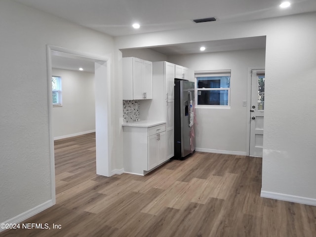 kitchen featuring white cabinetry, tasteful backsplash, light wood-type flooring, and stainless steel fridge