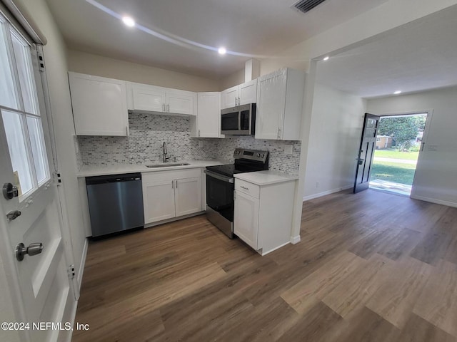 kitchen with appliances with stainless steel finishes, sink, backsplash, white cabinets, and dark wood-type flooring