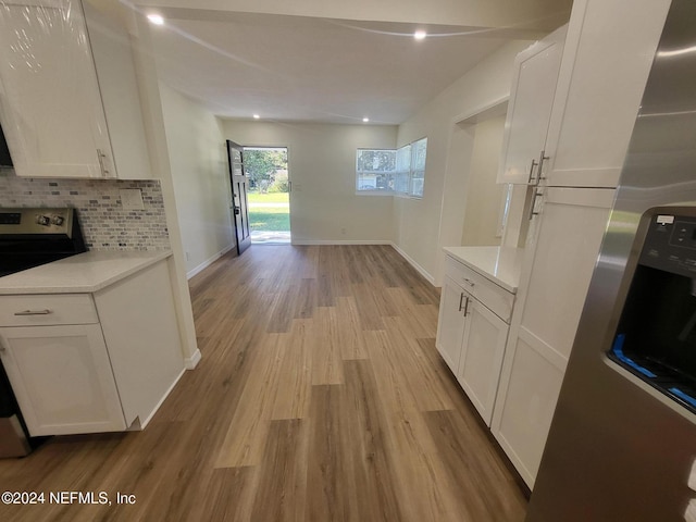 kitchen with backsplash, range, light wood-type flooring, and white cabinets