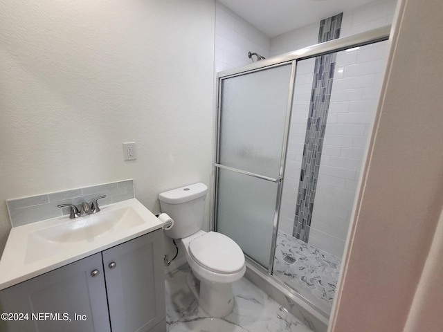 bathroom featuring toilet, a shower with shower door, and vanity