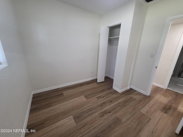 unfurnished bedroom featuring a closet and hardwood / wood-style flooring