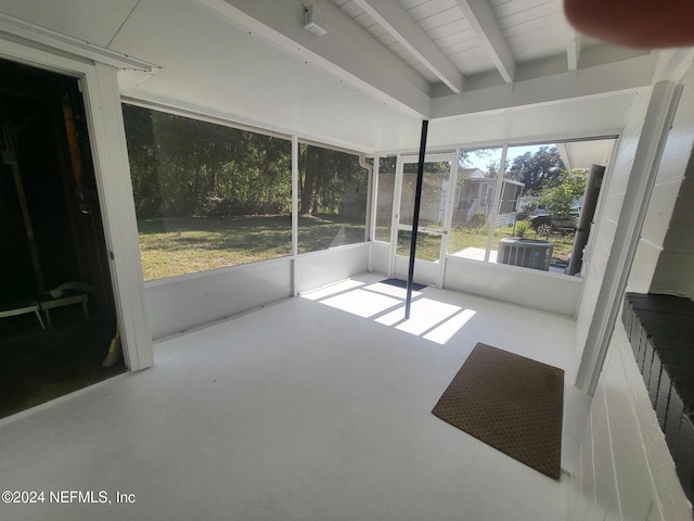 unfurnished sunroom featuring beam ceiling and plenty of natural light