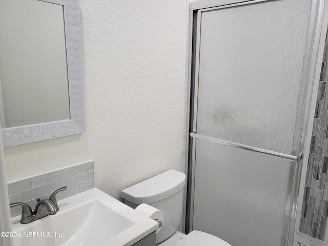 bathroom with toilet, walk in shower, vanity, and tasteful backsplash