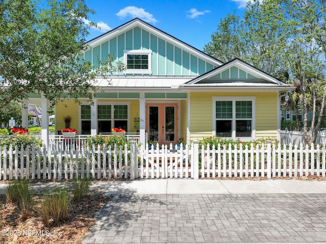 view of front of home featuring a fenced front yard, metal roof, covered porch, a standing seam roof, and board and batten siding