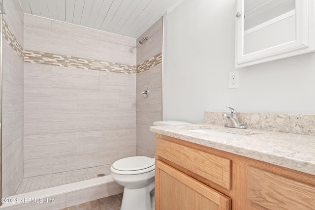 bathroom featuring toilet, vanity, and a tile shower