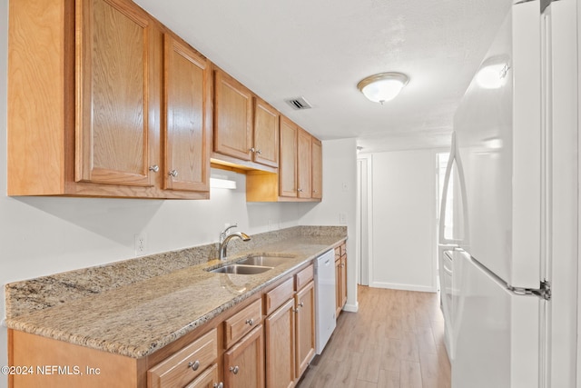 kitchen featuring sink, light hardwood / wood-style floors, light stone counters, and white appliances