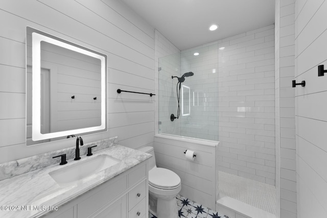 bathroom with tiled shower, vanity, and toilet