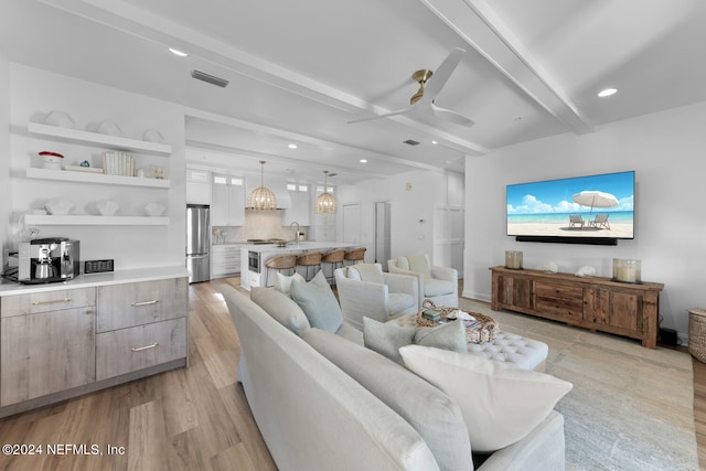 living room featuring light hardwood / wood-style floors, beam ceiling, sink, and ceiling fan