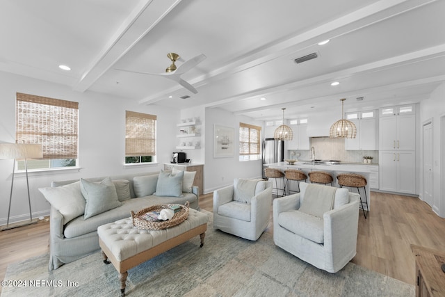 living room with beamed ceiling, light hardwood / wood-style flooring, and a healthy amount of sunlight