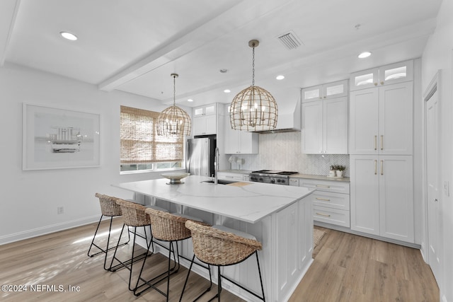 kitchen featuring an island with sink, white cabinetry, a chandelier, and stainless steel appliances