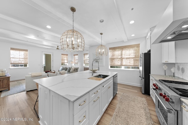 kitchen with stainless steel appliances, light hardwood / wood-style floors, a kitchen island with sink, and white cabinetry