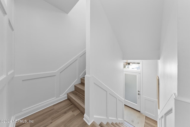 staircase with lofted ceiling and wood-type flooring