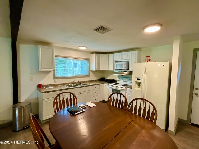 kitchen featuring light wood-type flooring, light stone counters, white cabinets, white appliances, and sink