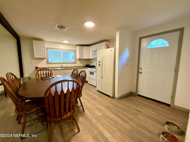 kitchen with white appliances, sink, light wood-type flooring, and white cabinetry