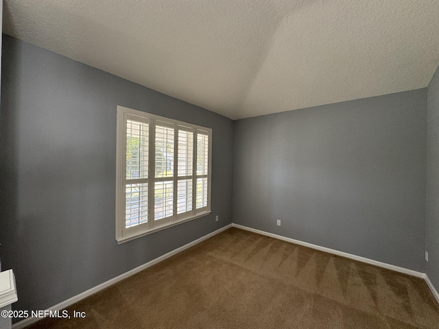 carpeted empty room with lofted ceiling, baseboards, and a textured ceiling