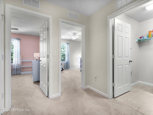 corridor with a textured ceiling and light colored carpet