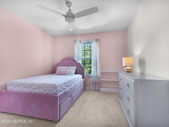 carpeted bedroom with ceiling fan and a textured ceiling