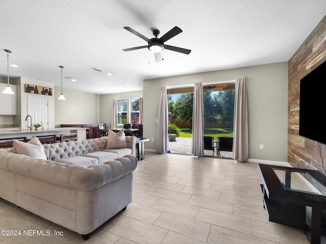 living room featuring a textured ceiling, sink, and ceiling fan