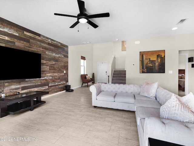 living room featuring ceiling fan and wood walls