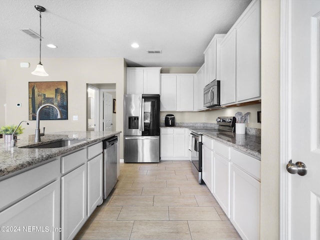 kitchen featuring white cabinetry, light stone counters, stainless steel appliances, and hanging light fixtures