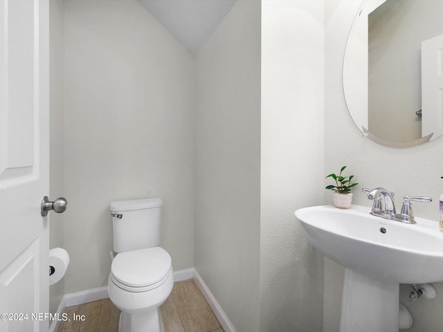 bathroom with sink, toilet, hardwood / wood-style flooring, and lofted ceiling