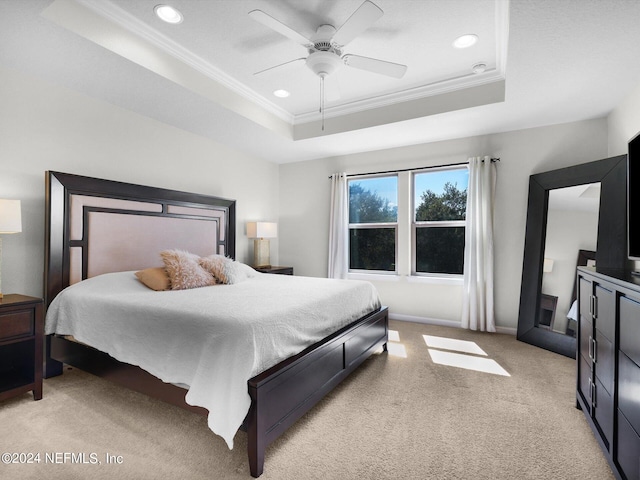 bedroom featuring crown molding, a tray ceiling, light colored carpet, and ceiling fan