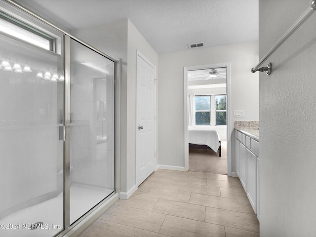 bathroom with vanity, ceiling fan, walk in shower, and a textured ceiling