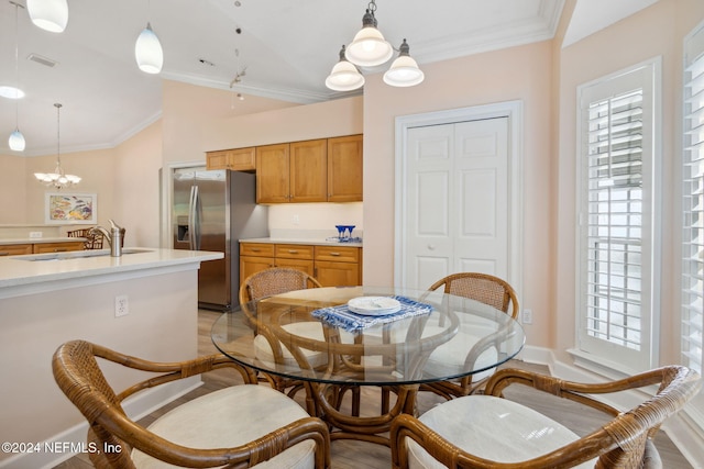 dining room featuring ornamental molding, sink, light wood-type flooring, and an inviting chandelier