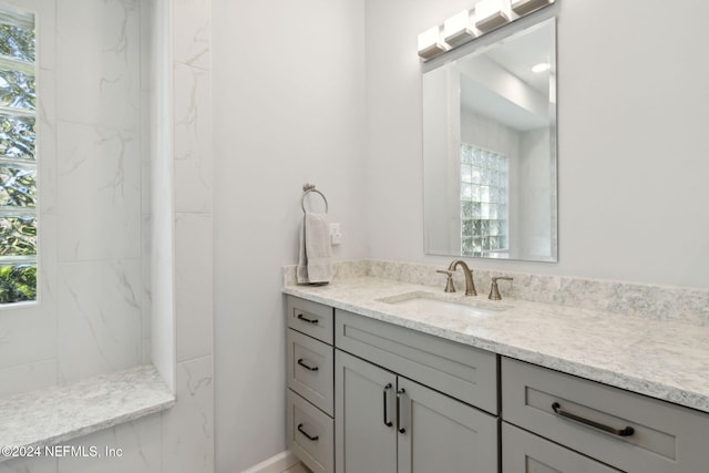 bathroom with vanity, plenty of natural light, and tiled shower