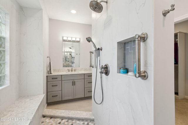 bathroom featuring a wealth of natural light, vanity, and a tile shower