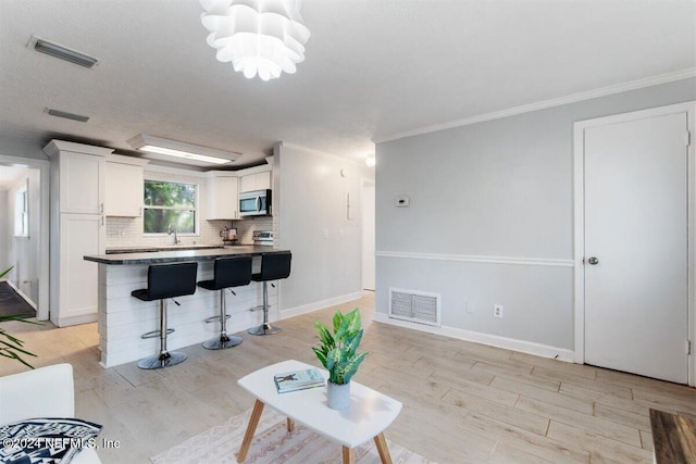 living room featuring light hardwood / wood-style flooring, crown molding, a chandelier, and sink