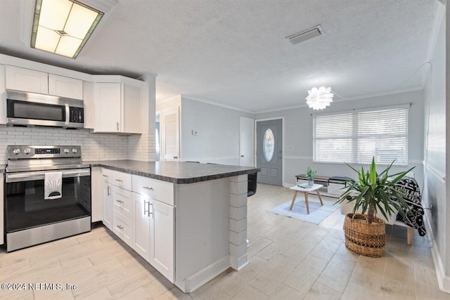 kitchen featuring appliances with stainless steel finishes, kitchen peninsula, white cabinets, and crown molding