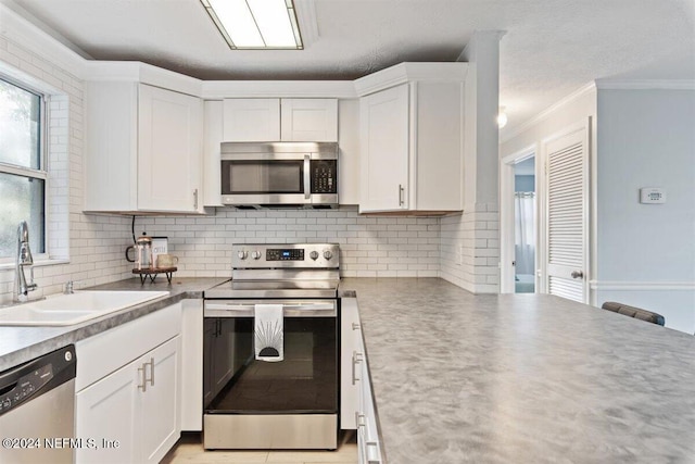 kitchen featuring appliances with stainless steel finishes, white cabinets, sink, and backsplash